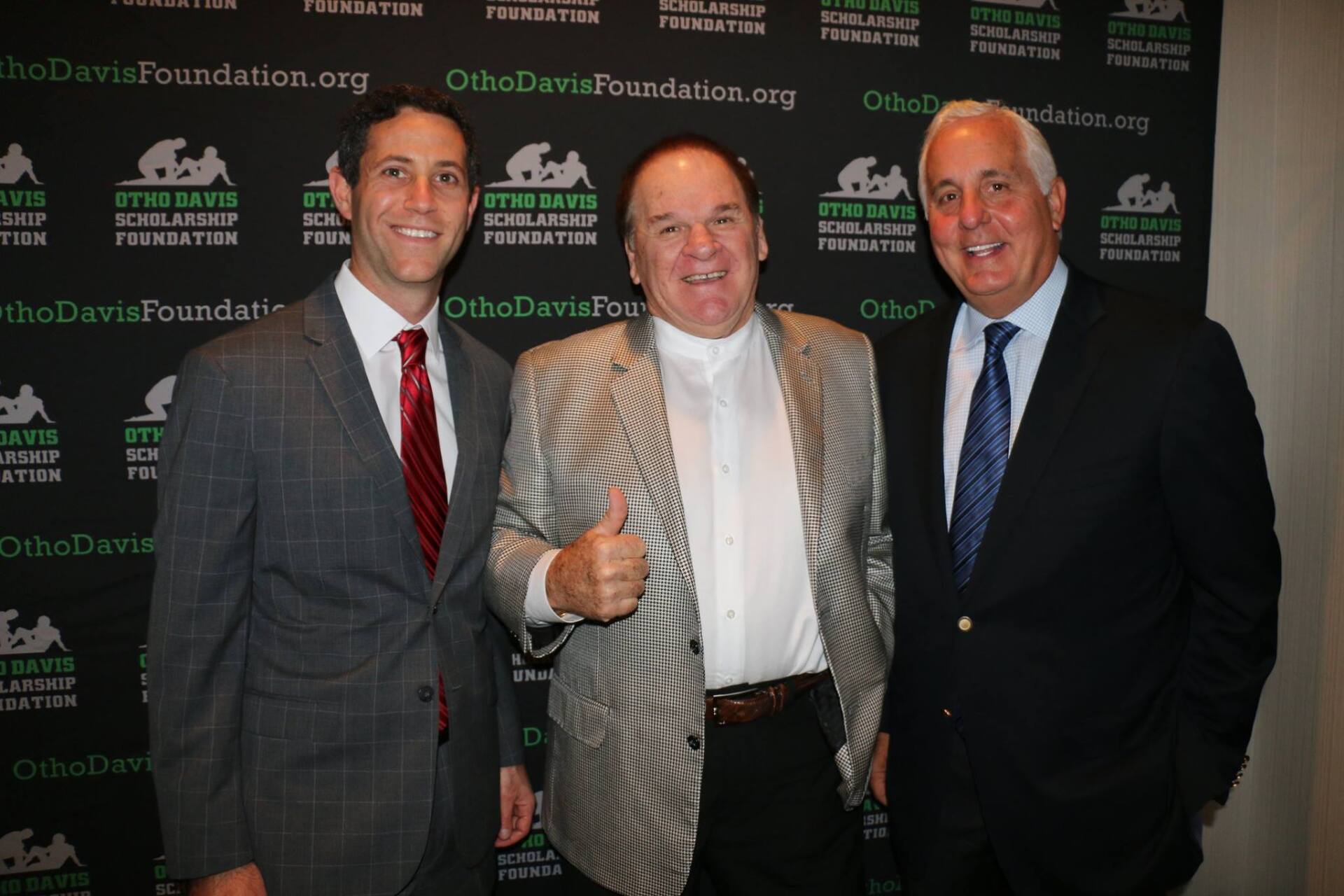 Three men in suits and ties are posing for a picture and one of them is giving a thumbs up