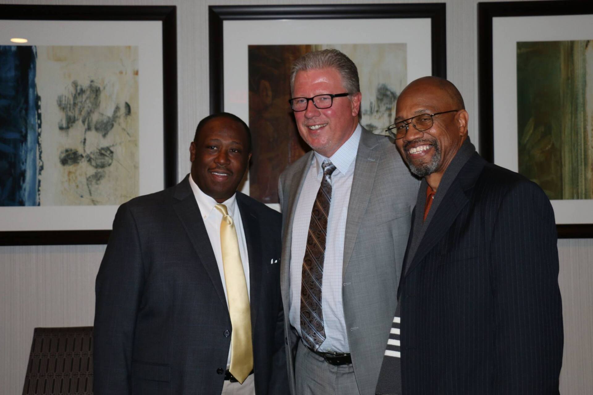 Three men in suits and ties are posing for a picture