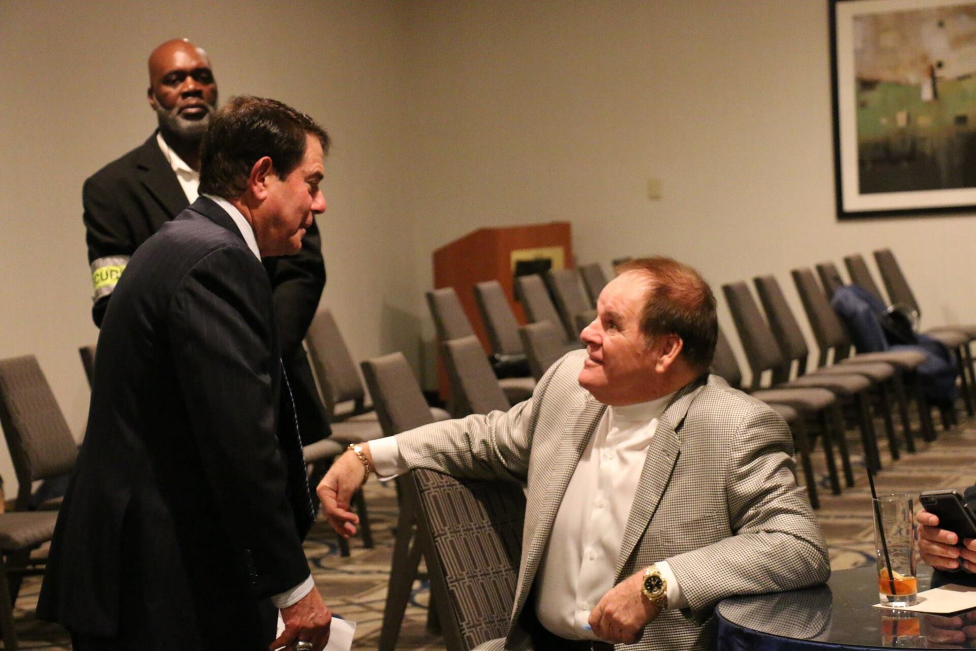 Two men are talking to each other in a room with chairs.