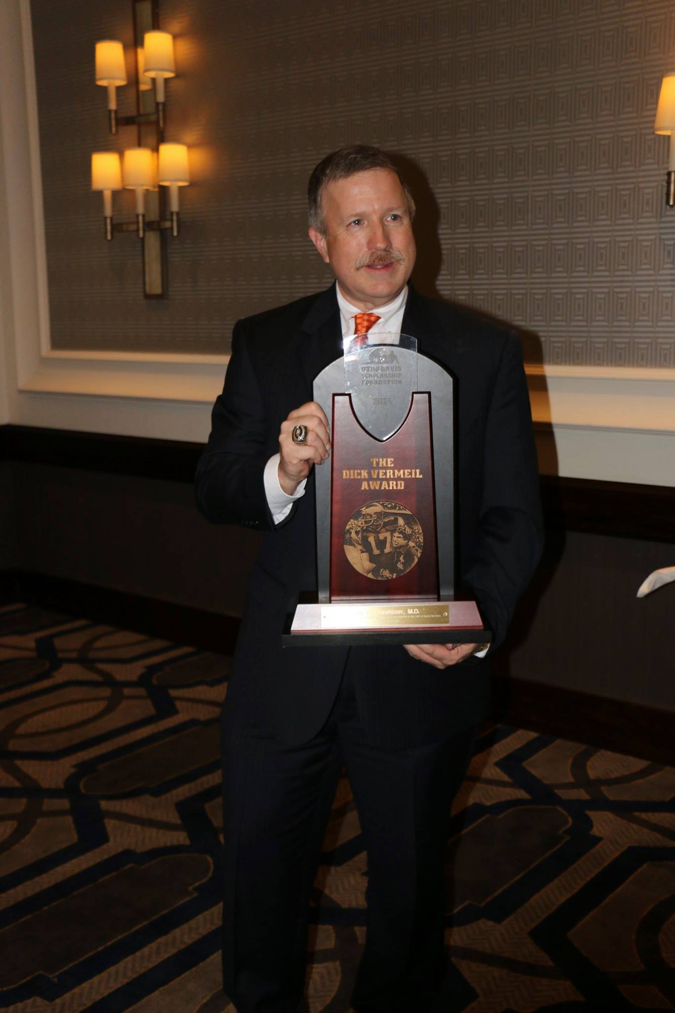 A man in a suit and tie is holding a trophy