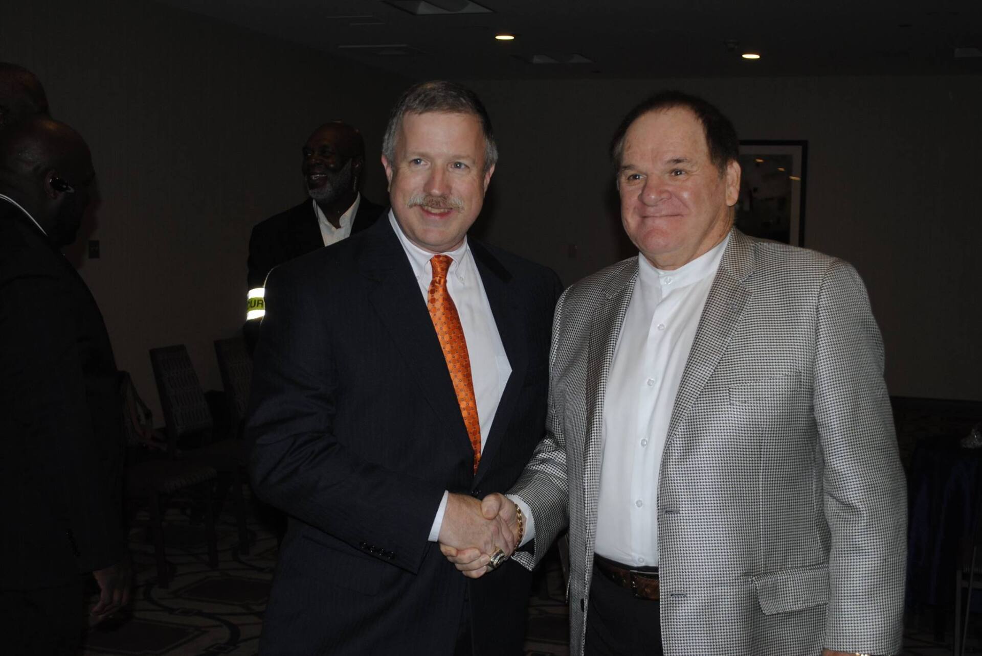 Two men in suits shaking hands in a dark room