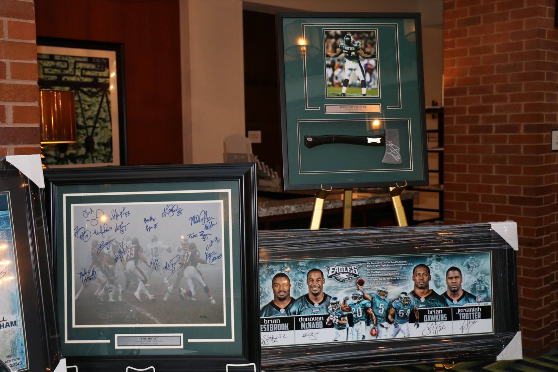 A group of framed pictures are sitting on a table in front of a brick wall