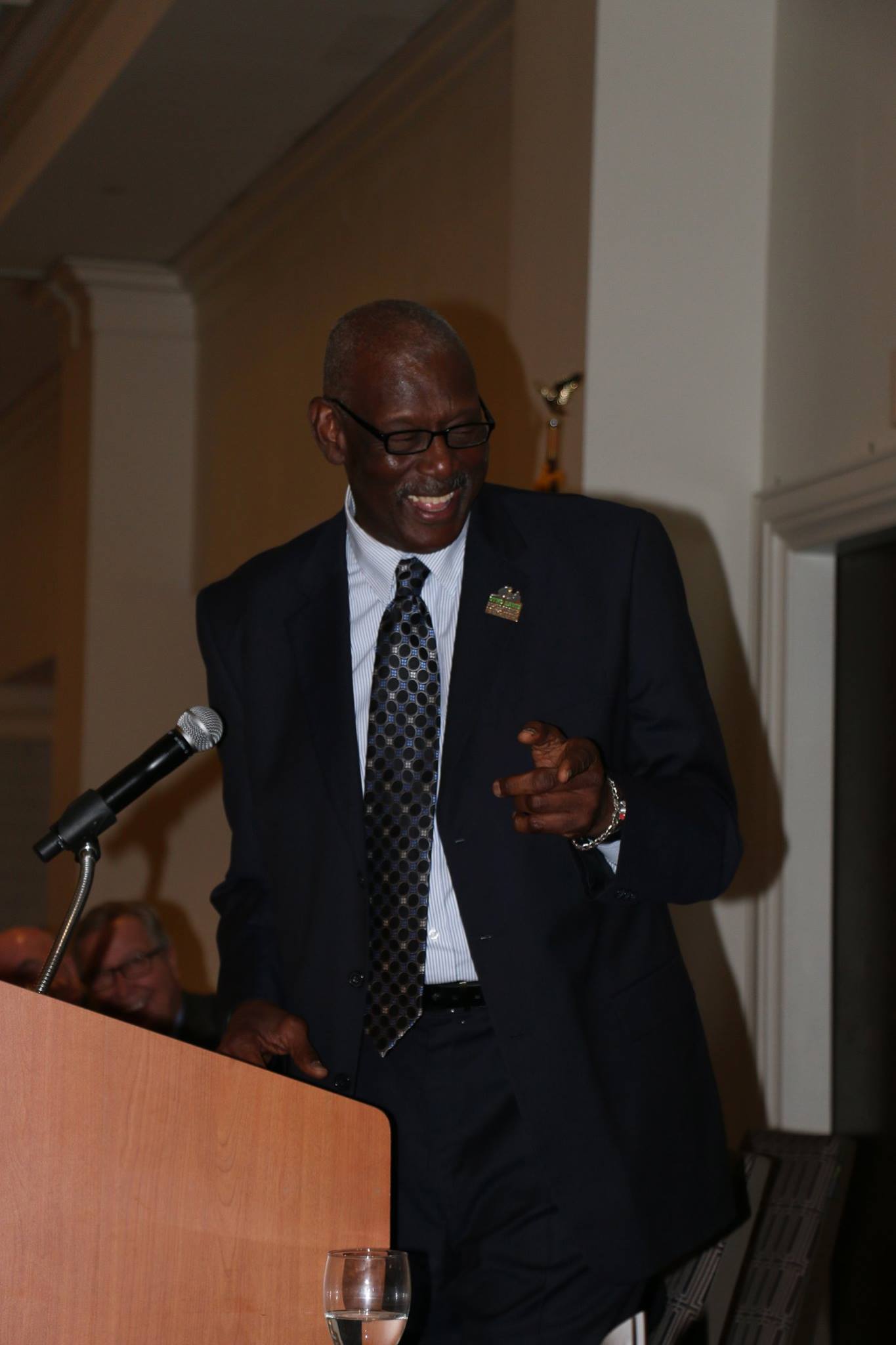 A man in a suit and tie is speaking into a microphone