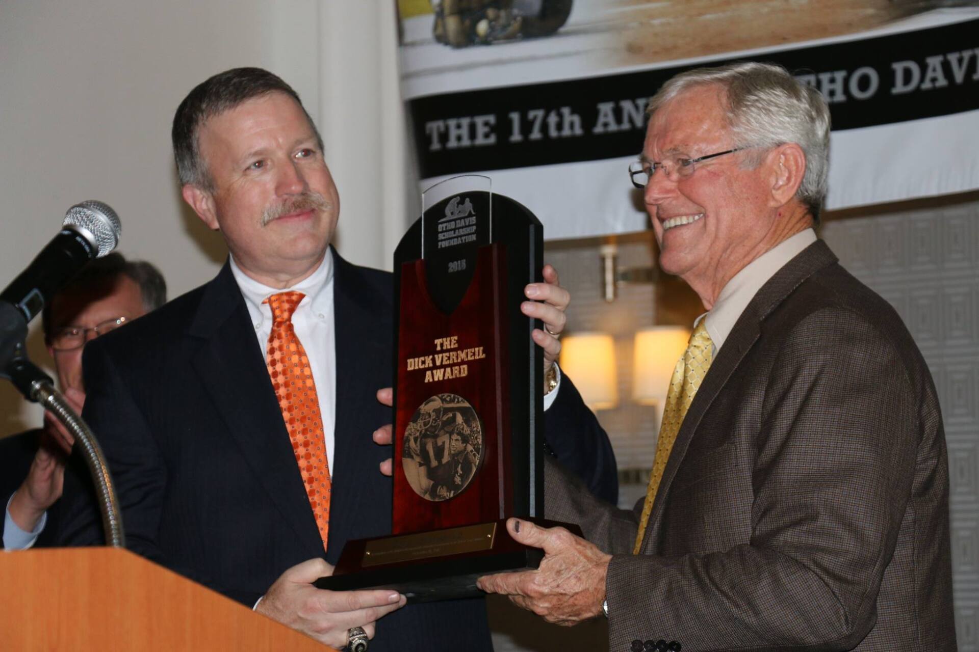 Two men are holding a plaque that says the 17th
