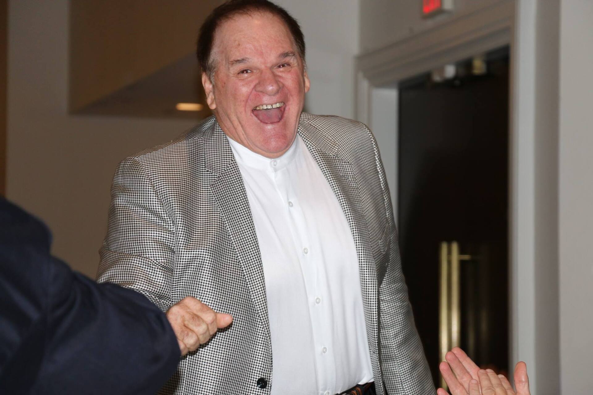 A man in a suit is laughing while standing next to another man.