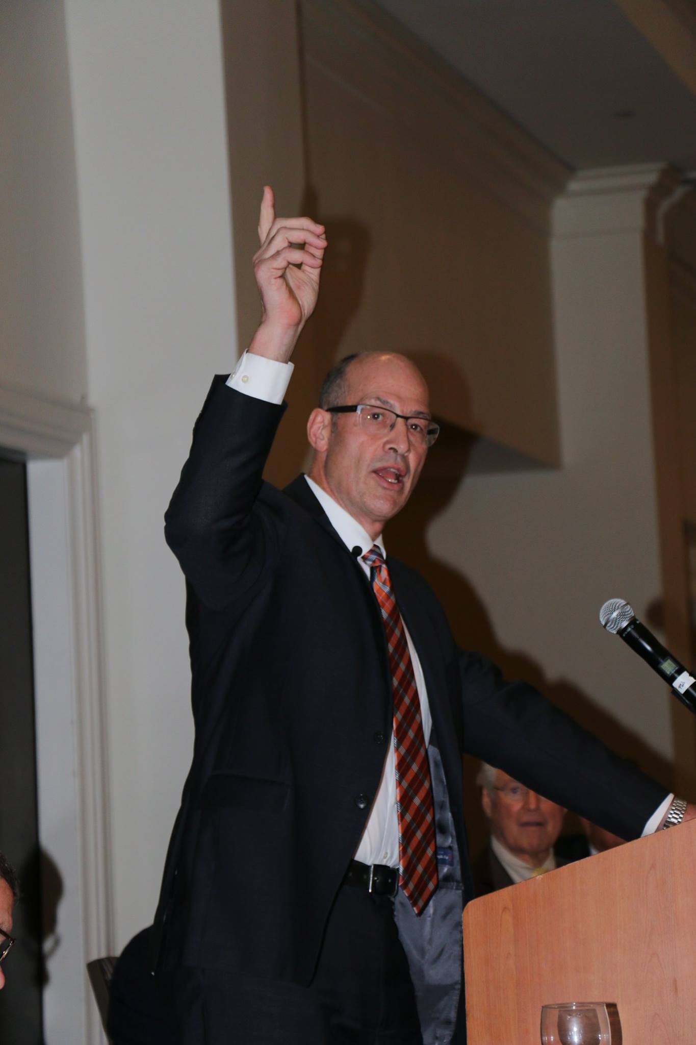 A man in a suit and tie is giving a speech at a podium