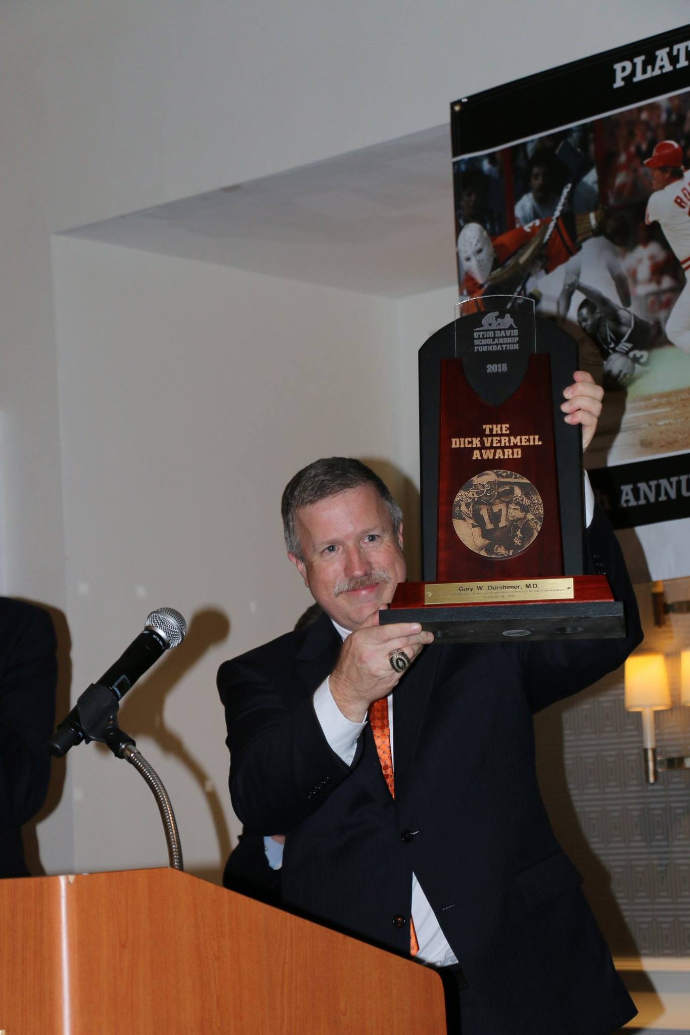 A man in a suit is holding a trophy in front of a microphone