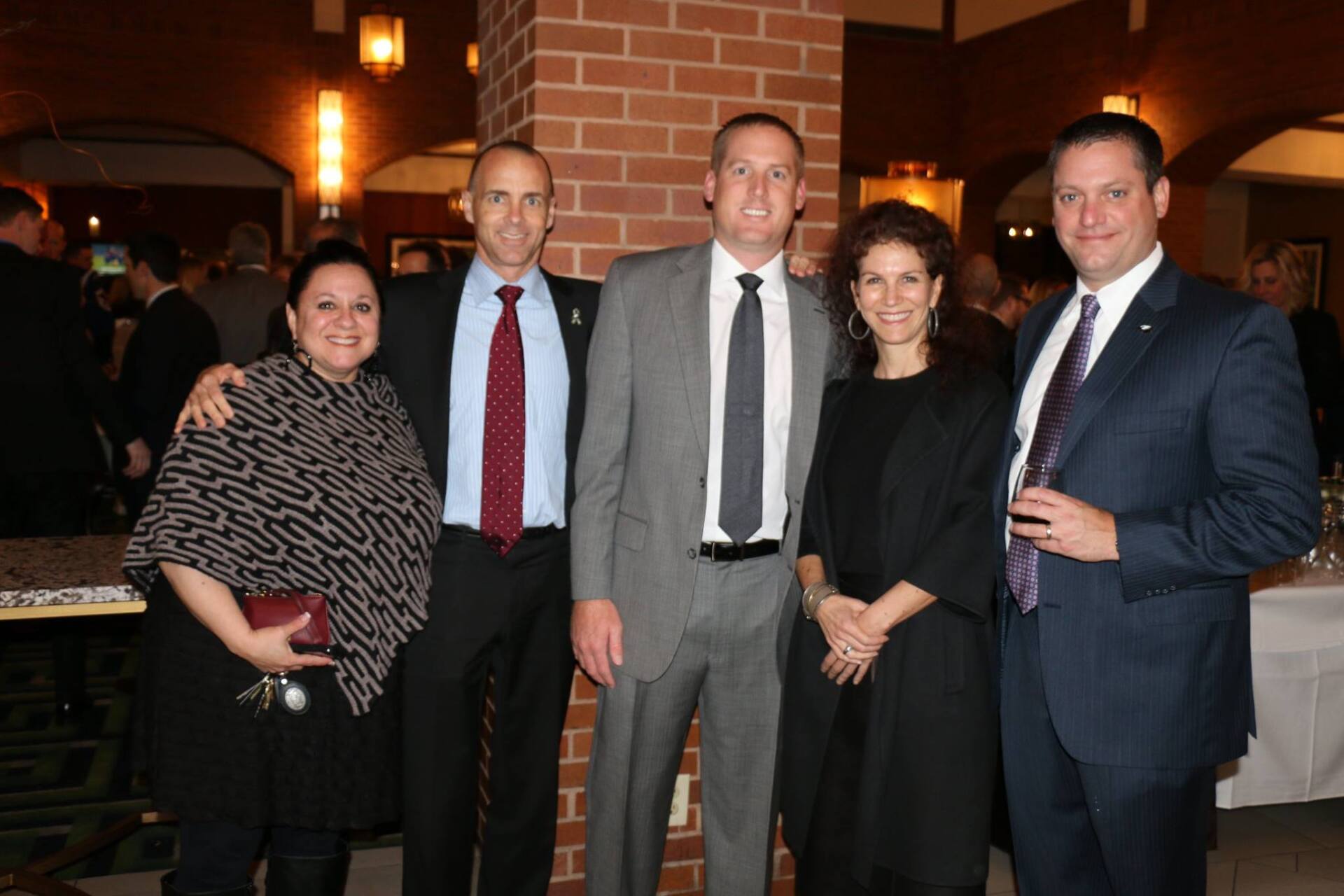 A group of people posing for a picture in front of a brick wall