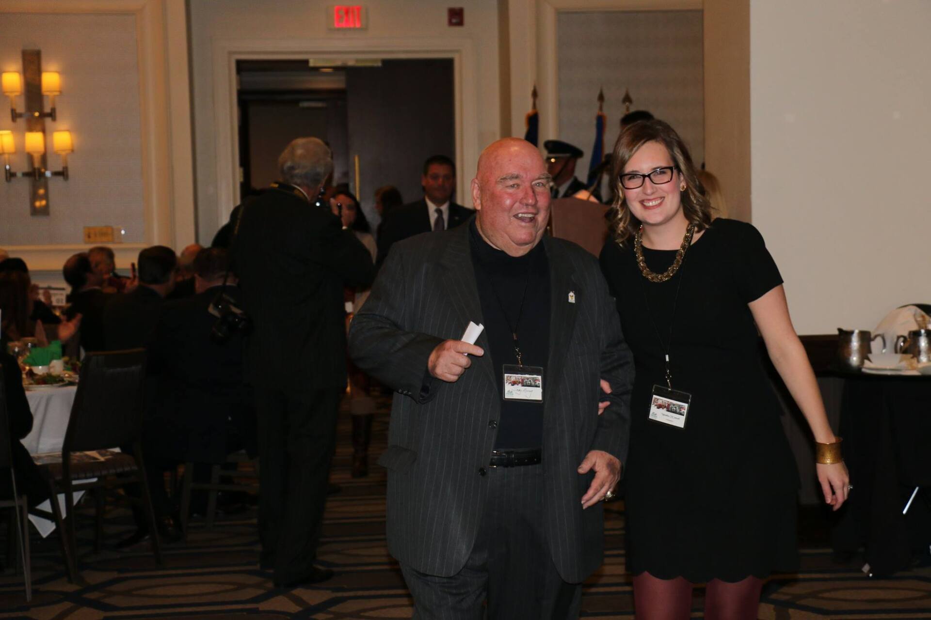 A man in a suit and a woman in a black dress pose for a picture