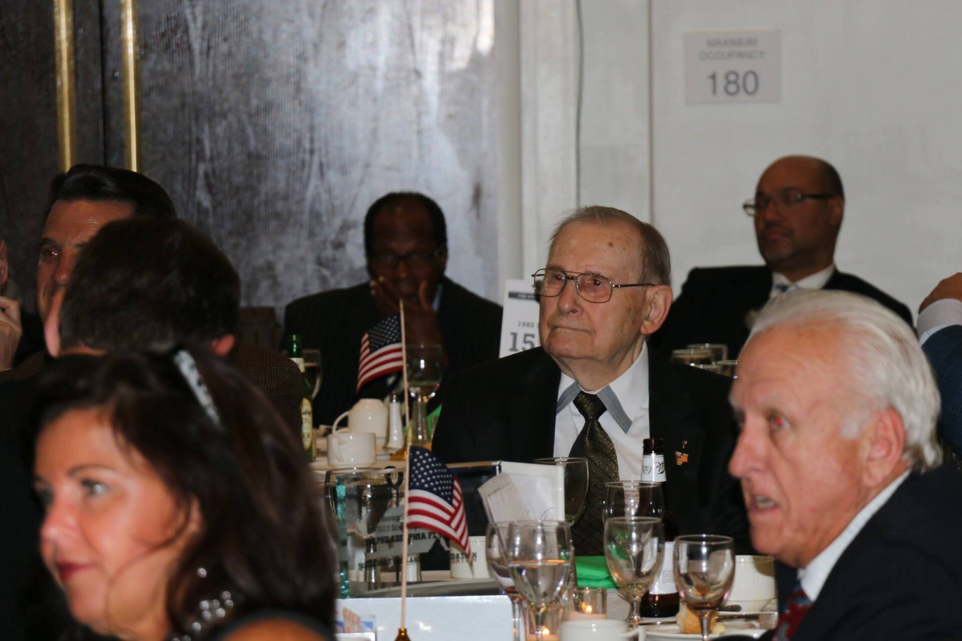 A group of people sitting at a table with a sign that says 160