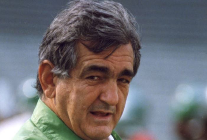 A man with gray hair and a green shirt is looking at the camera.