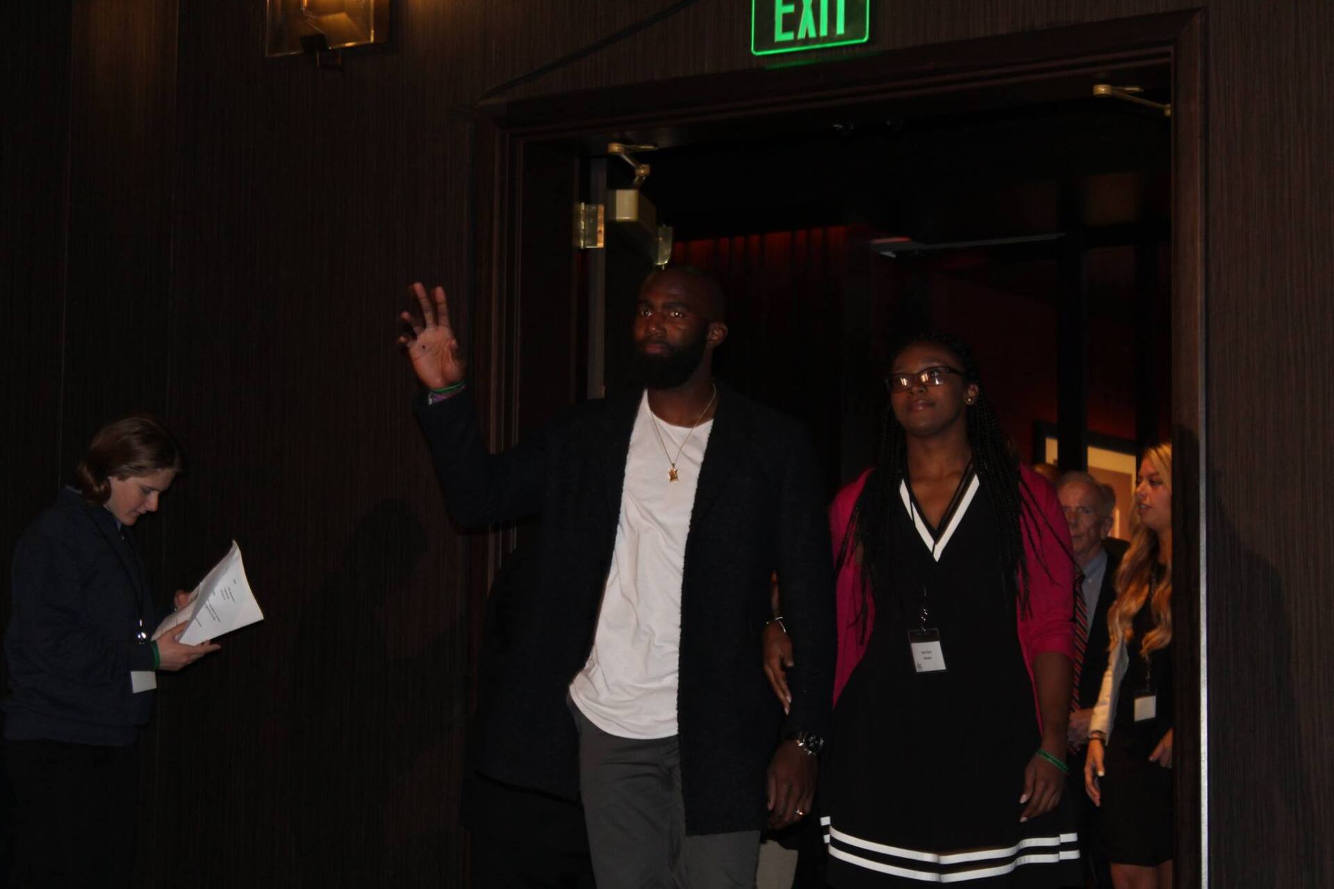 A man and a woman are walking through an exit door.