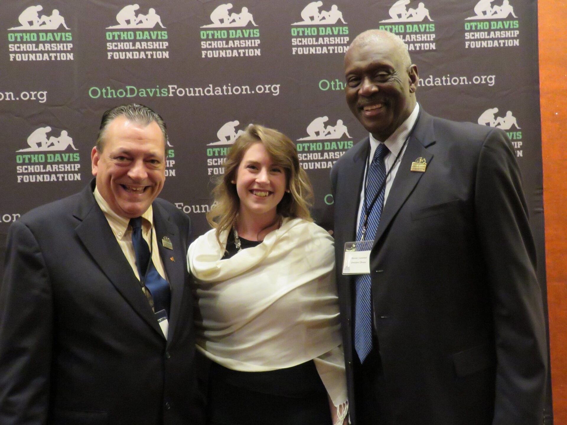 Three people posing for a picture in front of a wall that says ohio davis