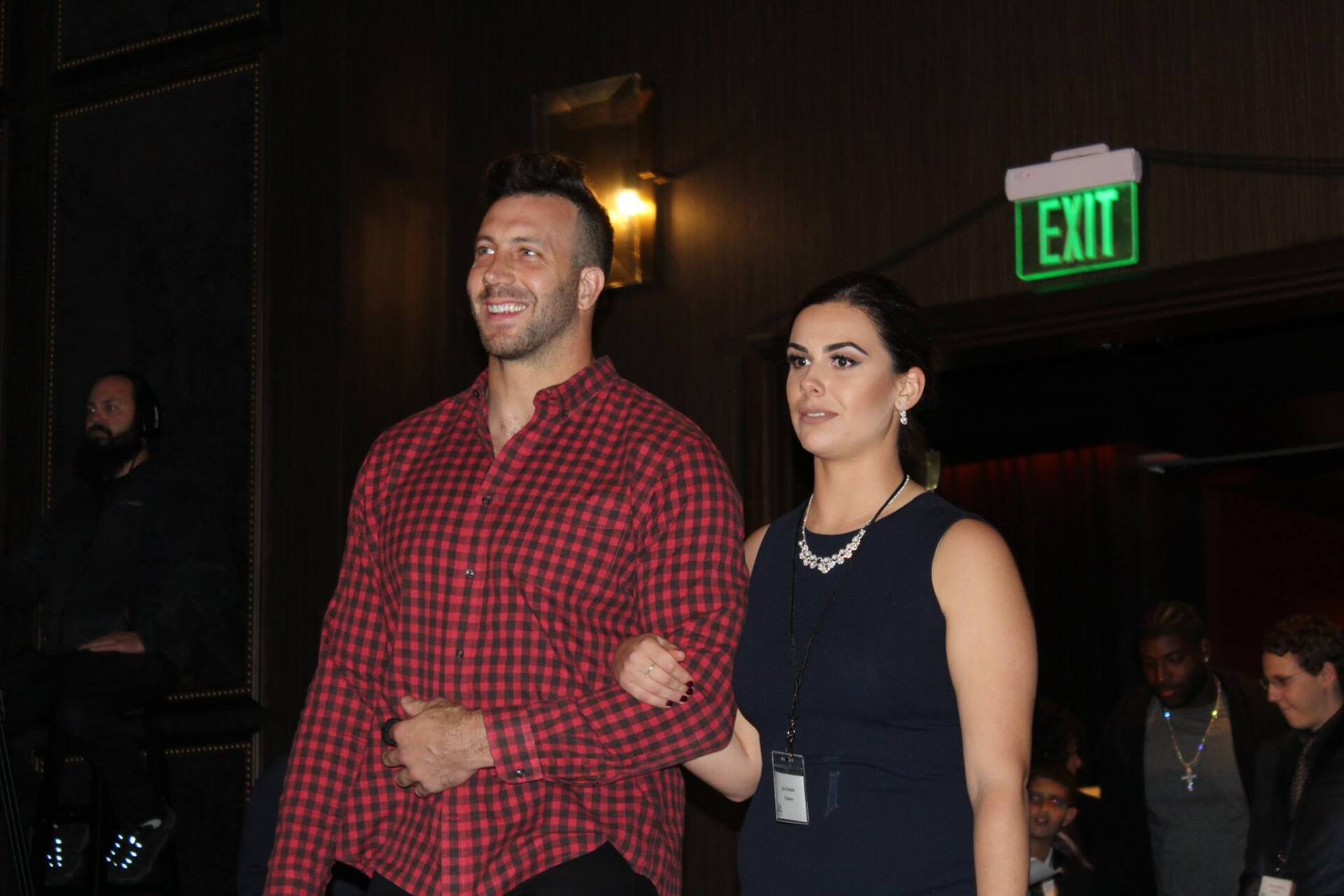 A man and a woman are walking in front of an exit sign.