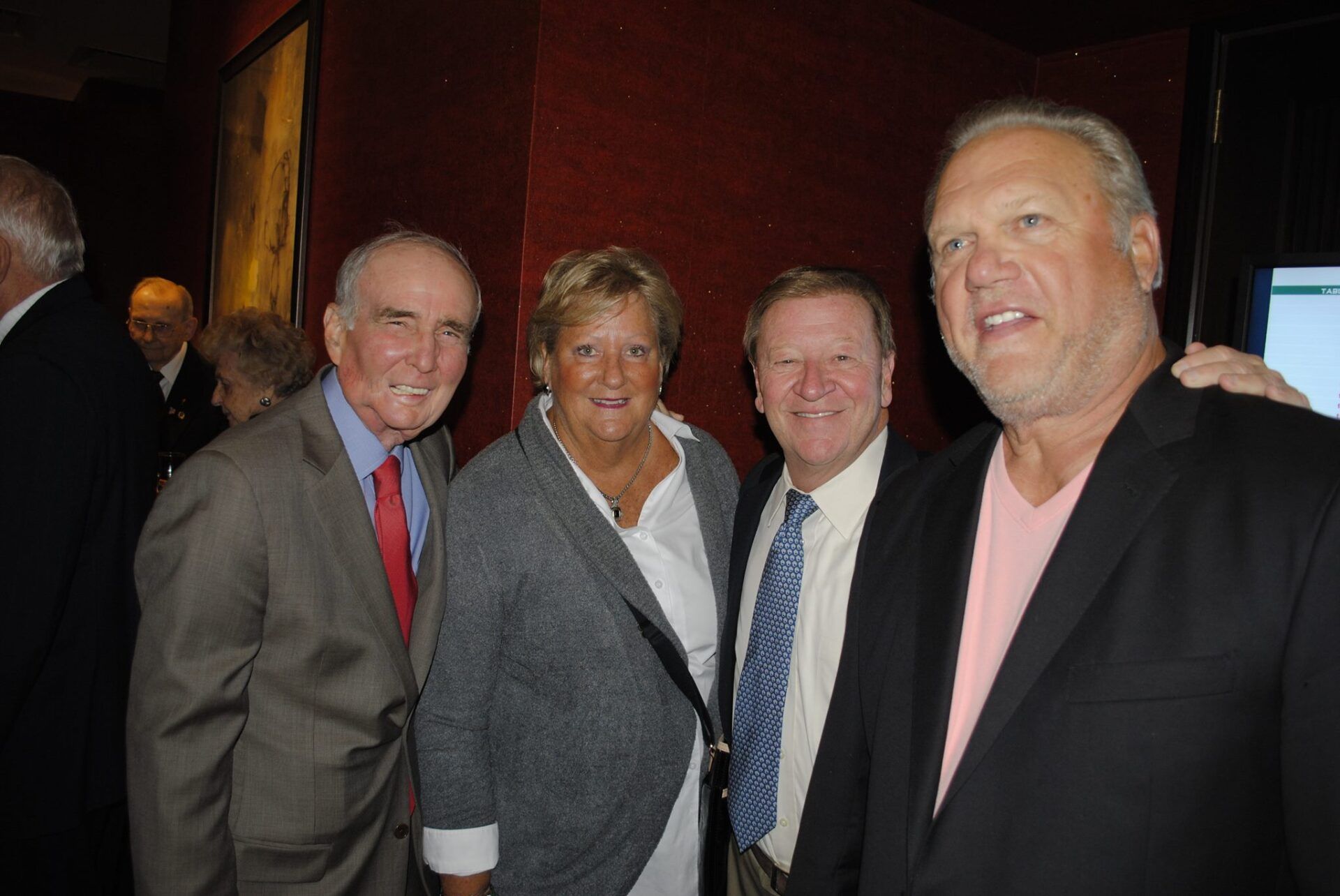 Three men and a woman are posing for a picture together