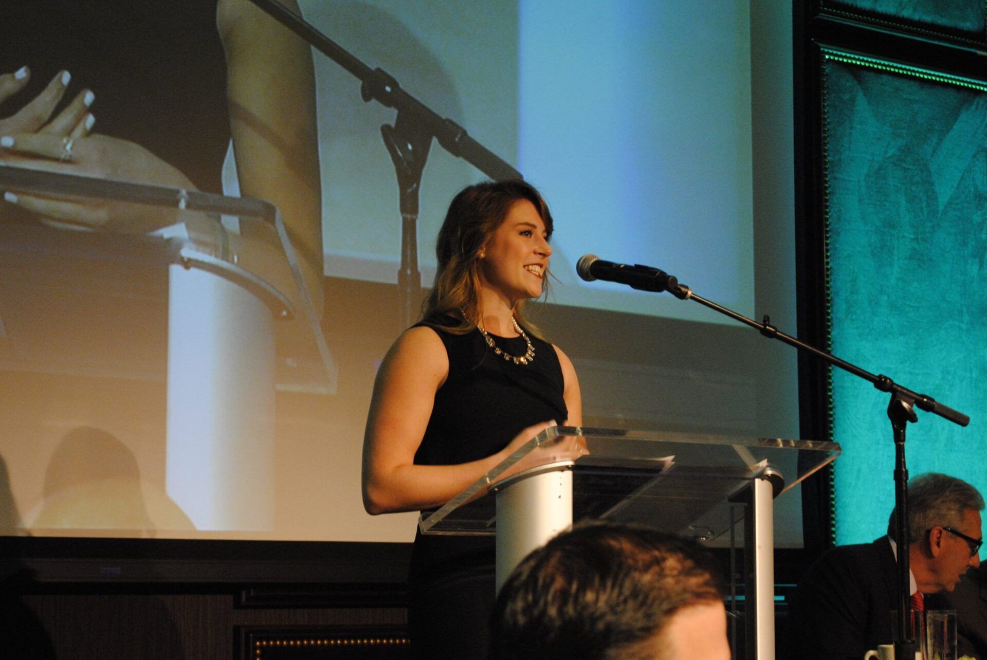 A woman is standing at a podium speaking into a microphone.