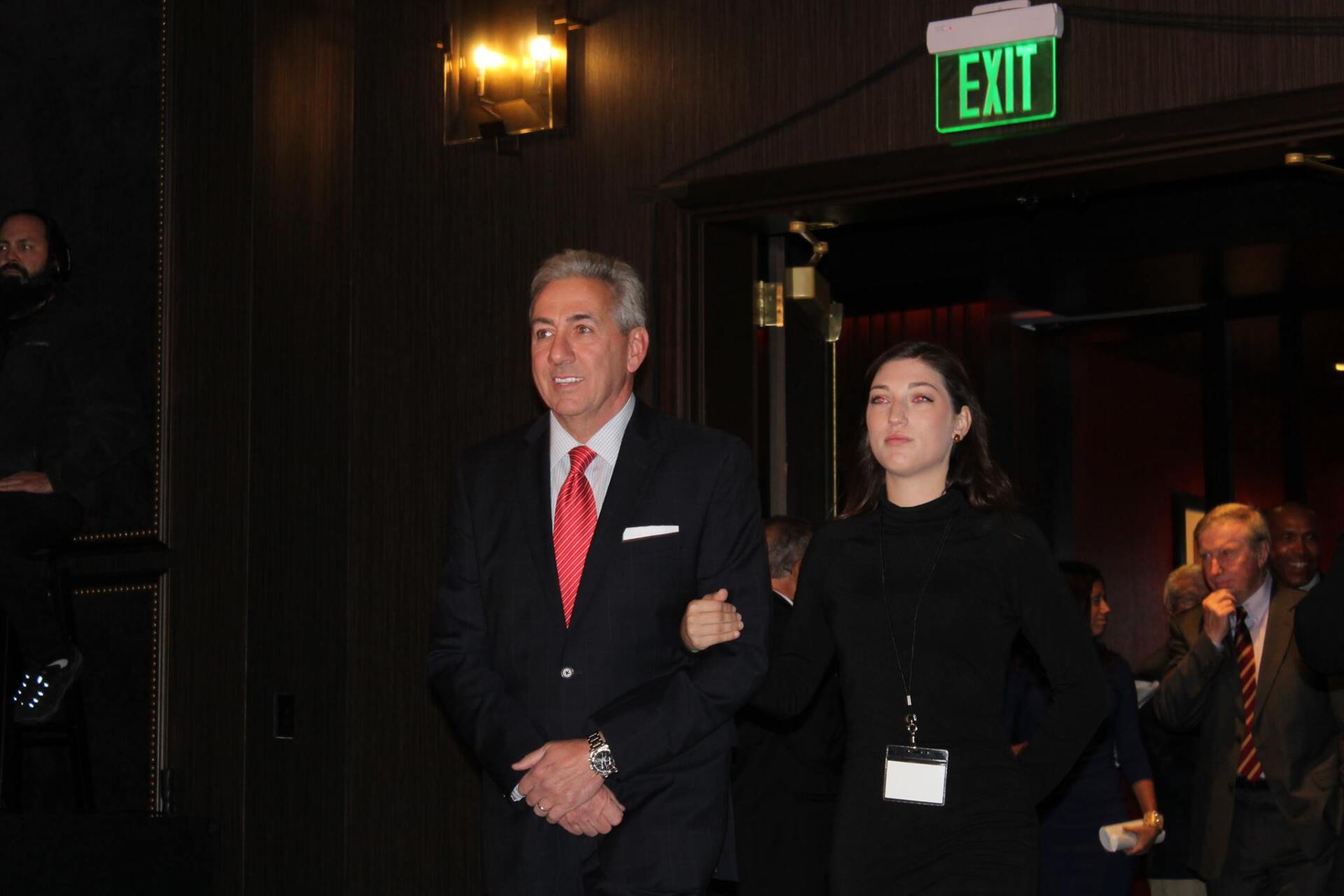 A man and a woman are walking in front of an exit sign.