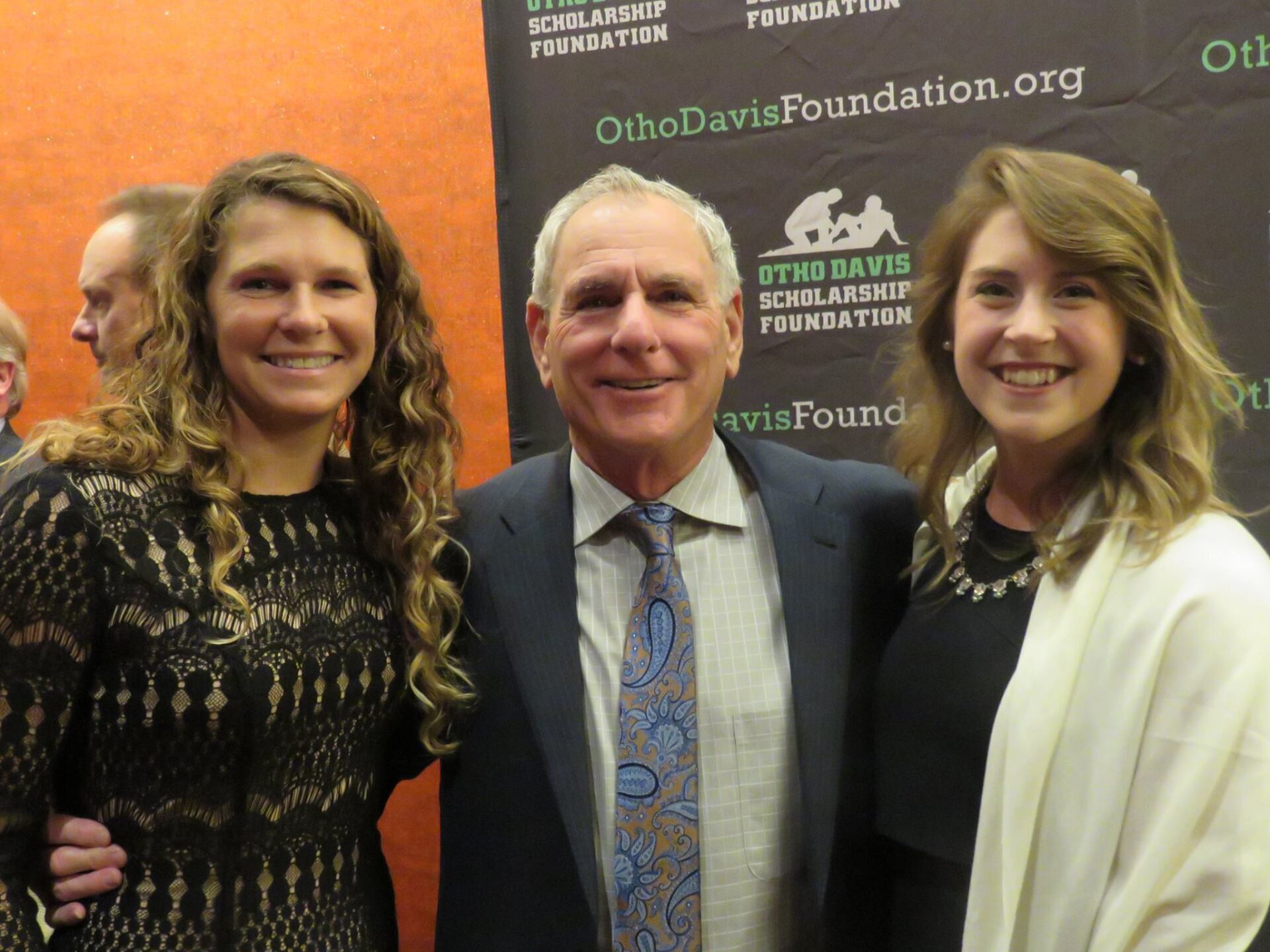 A man in a suit and tie poses with two women