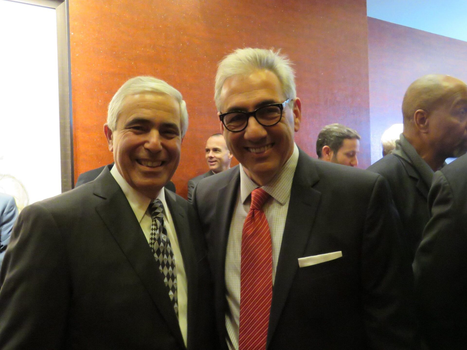 Two men in suits and ties are posing for a picture.