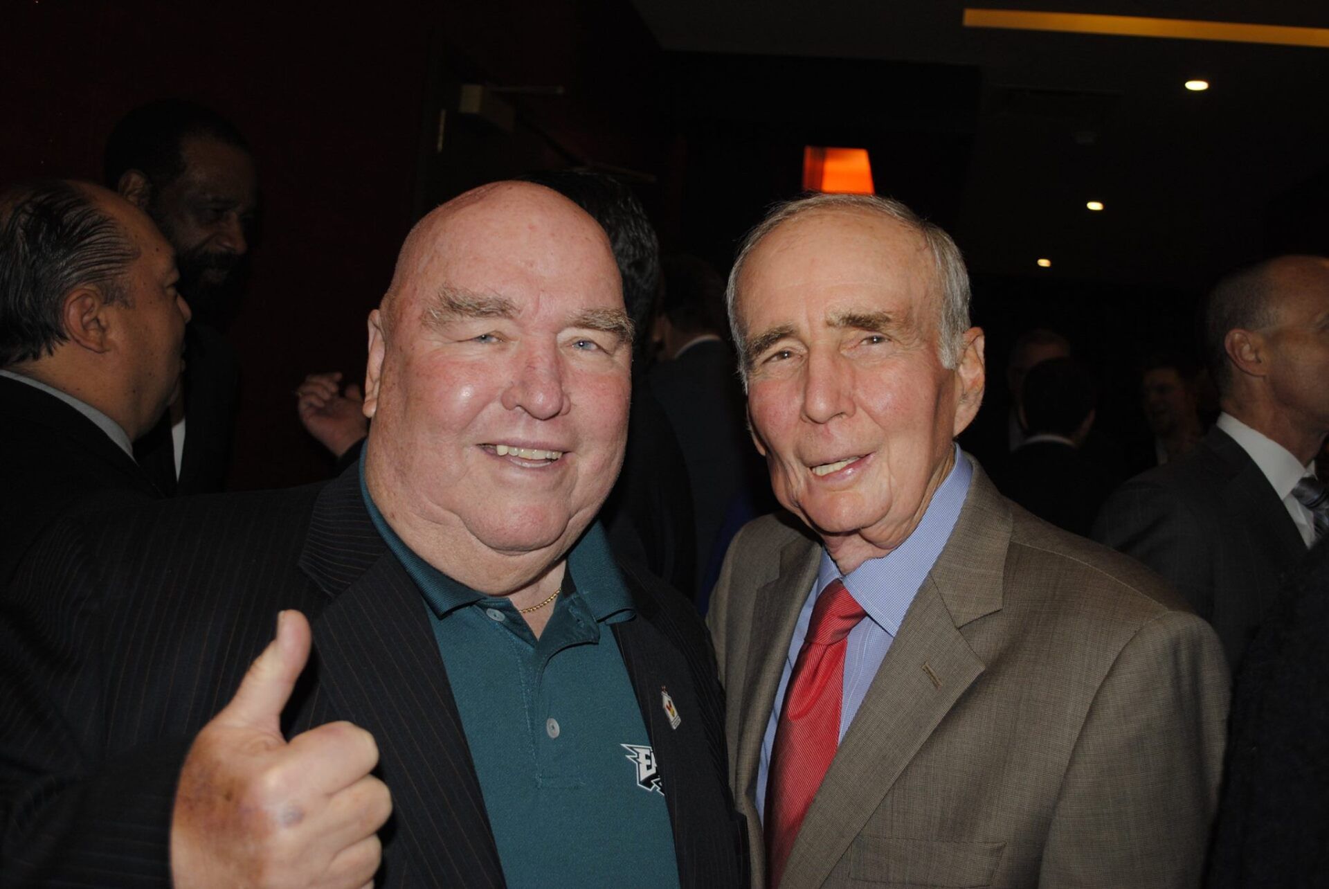 Two men are posing for a picture and one is giving a thumbs up