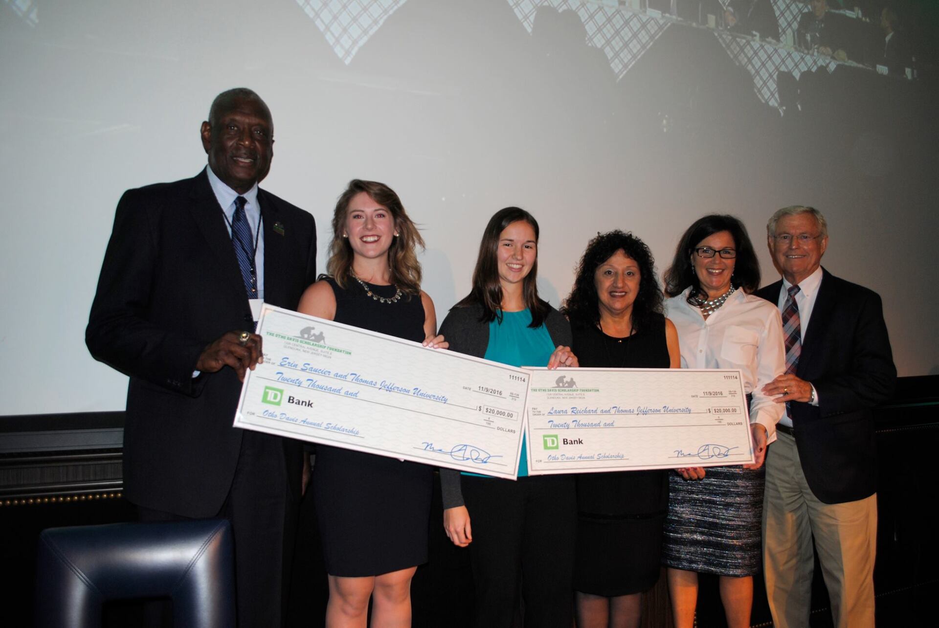 A group of people standing next to each other holding cheques.
