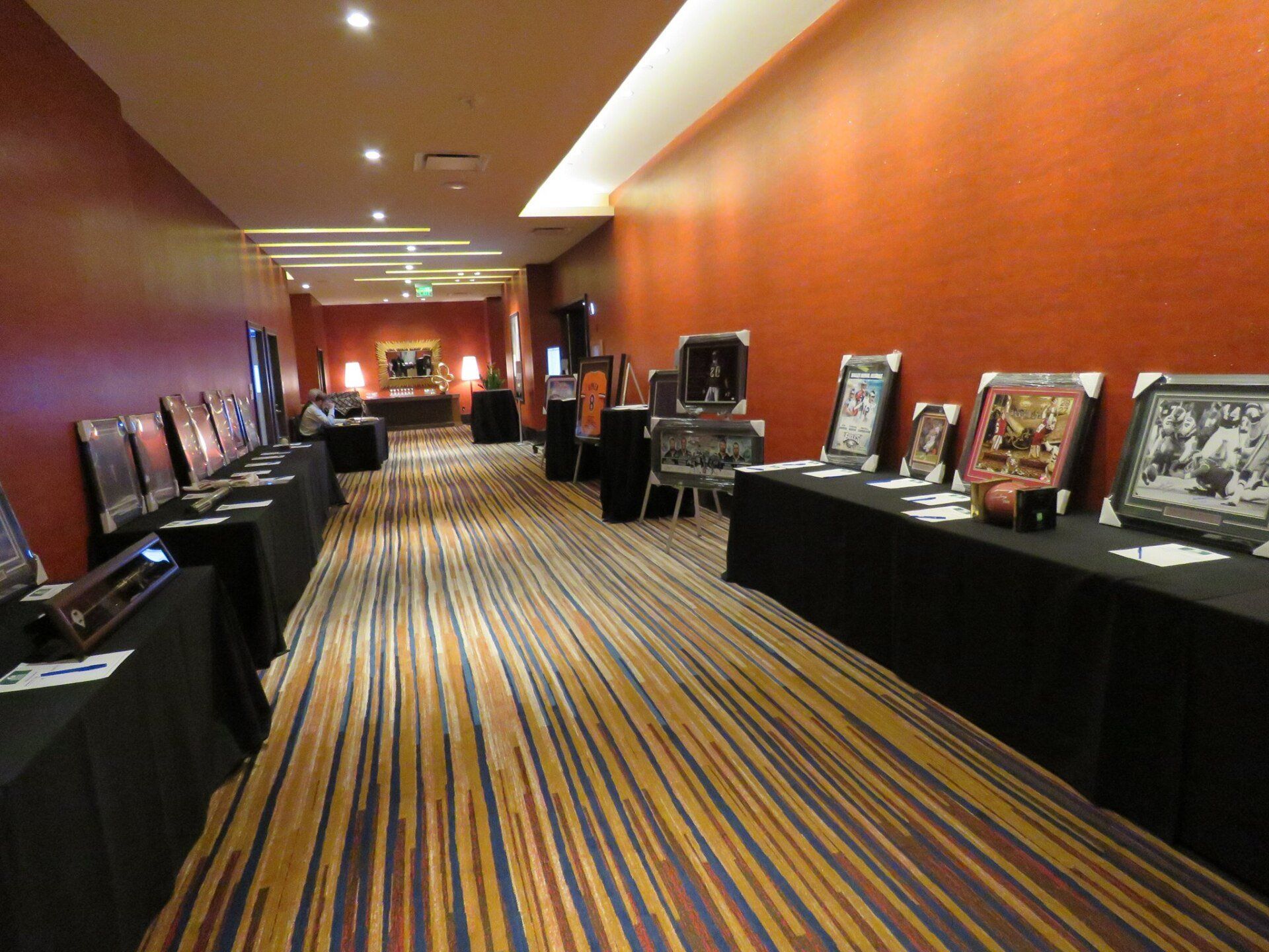 A long hallway with tables and pictures on them