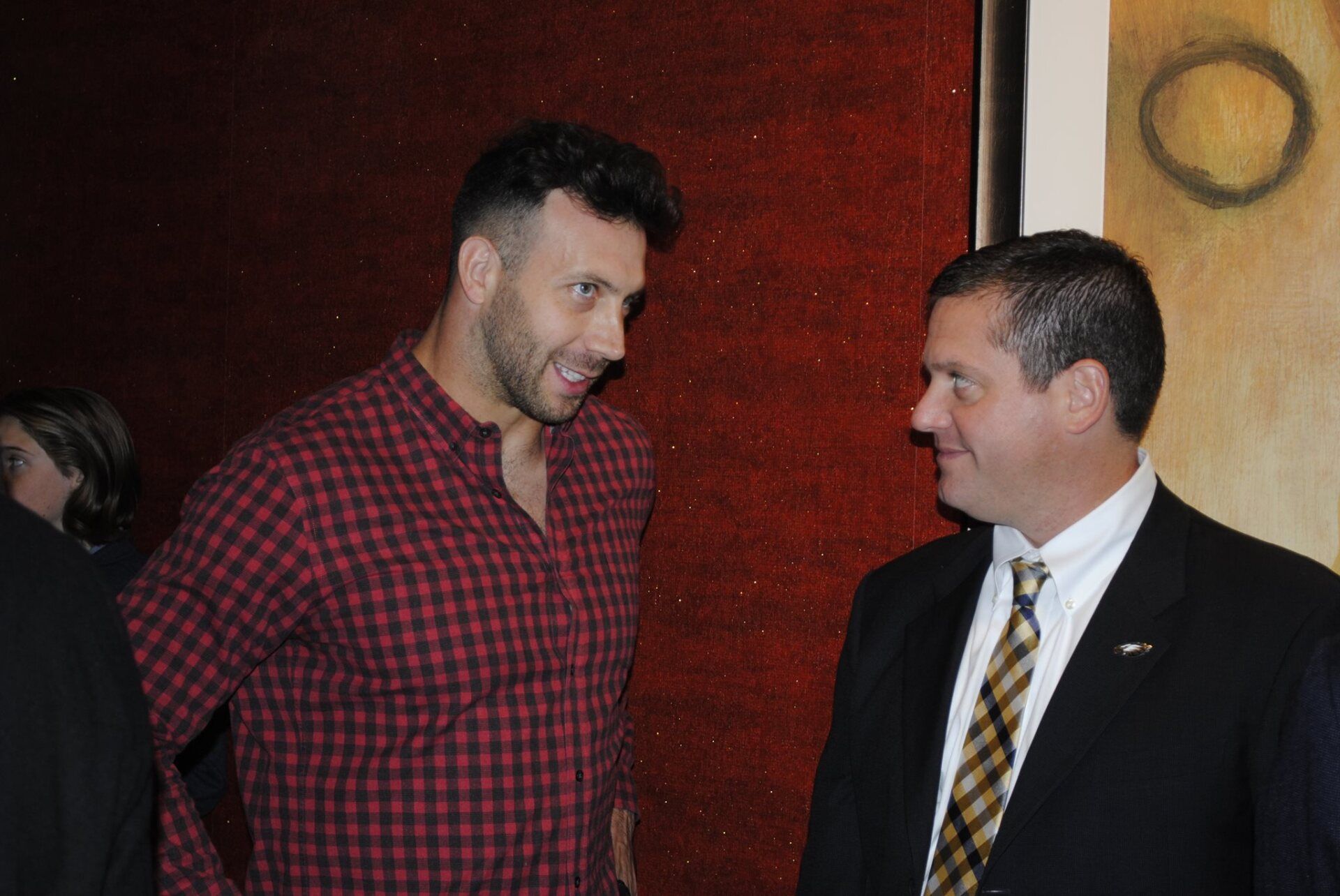 Two men in suits are standing next to each other and talking.