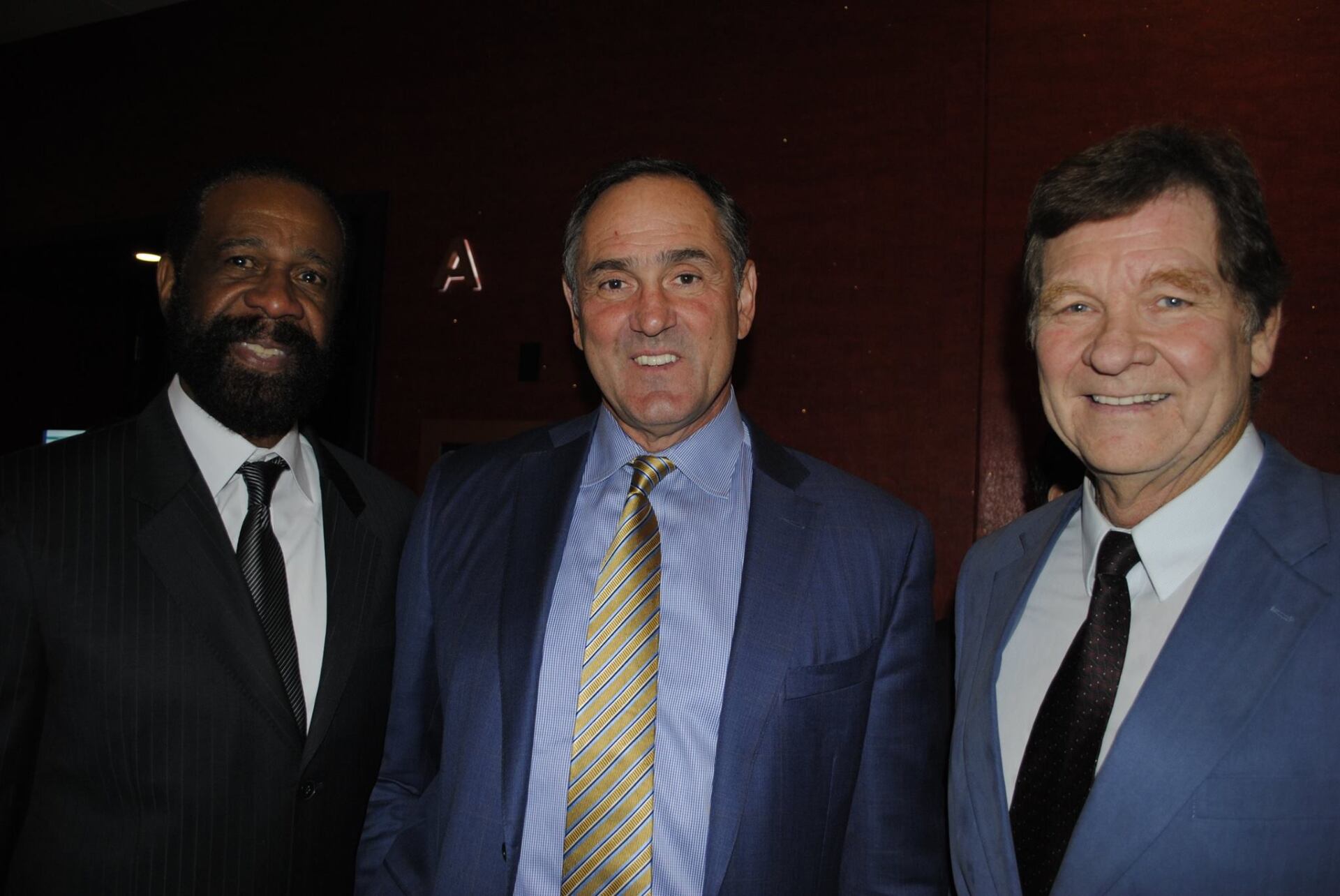 Three men in suits and ties are posing for a picture.