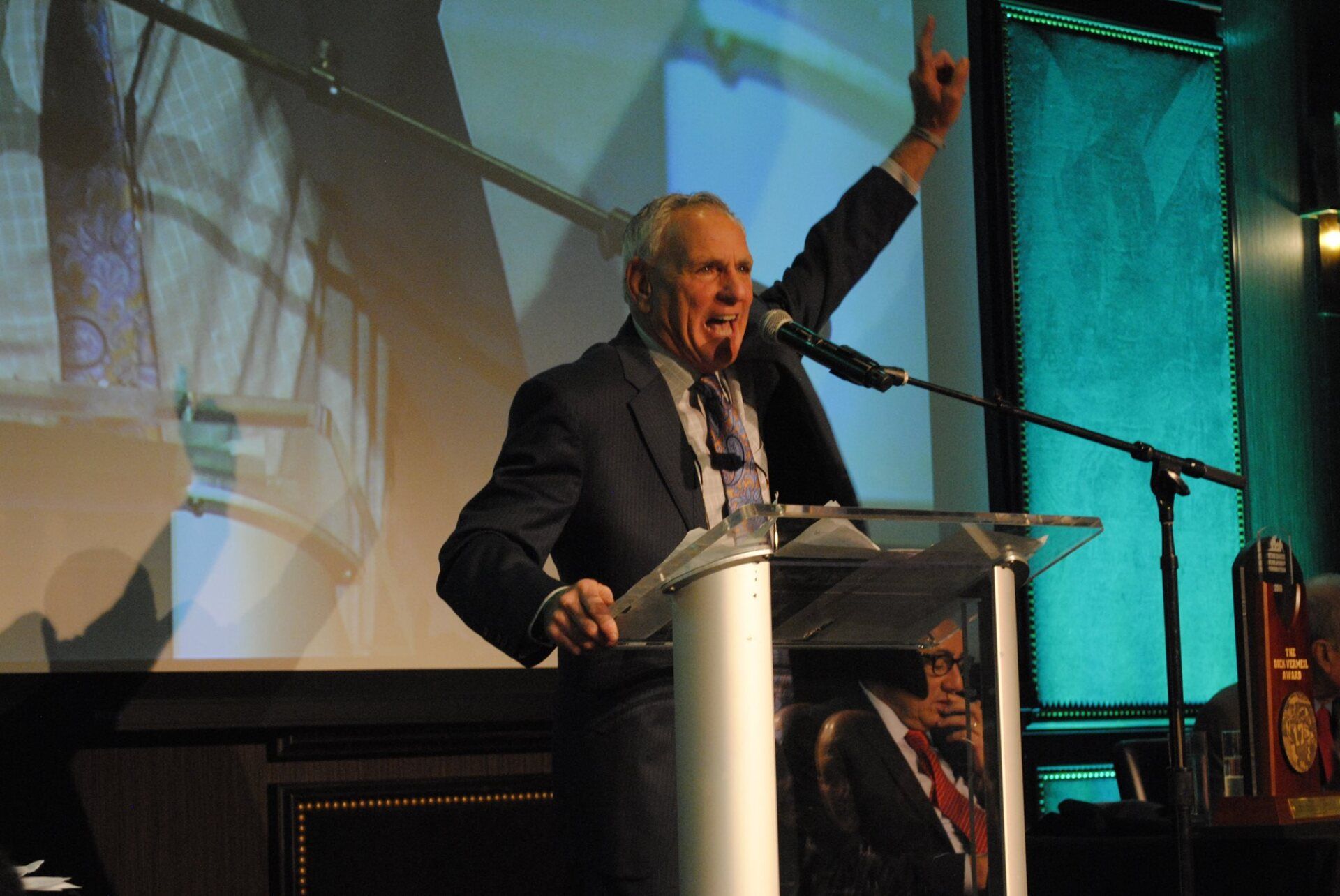 A man in a suit and tie is giving a speech at a podium