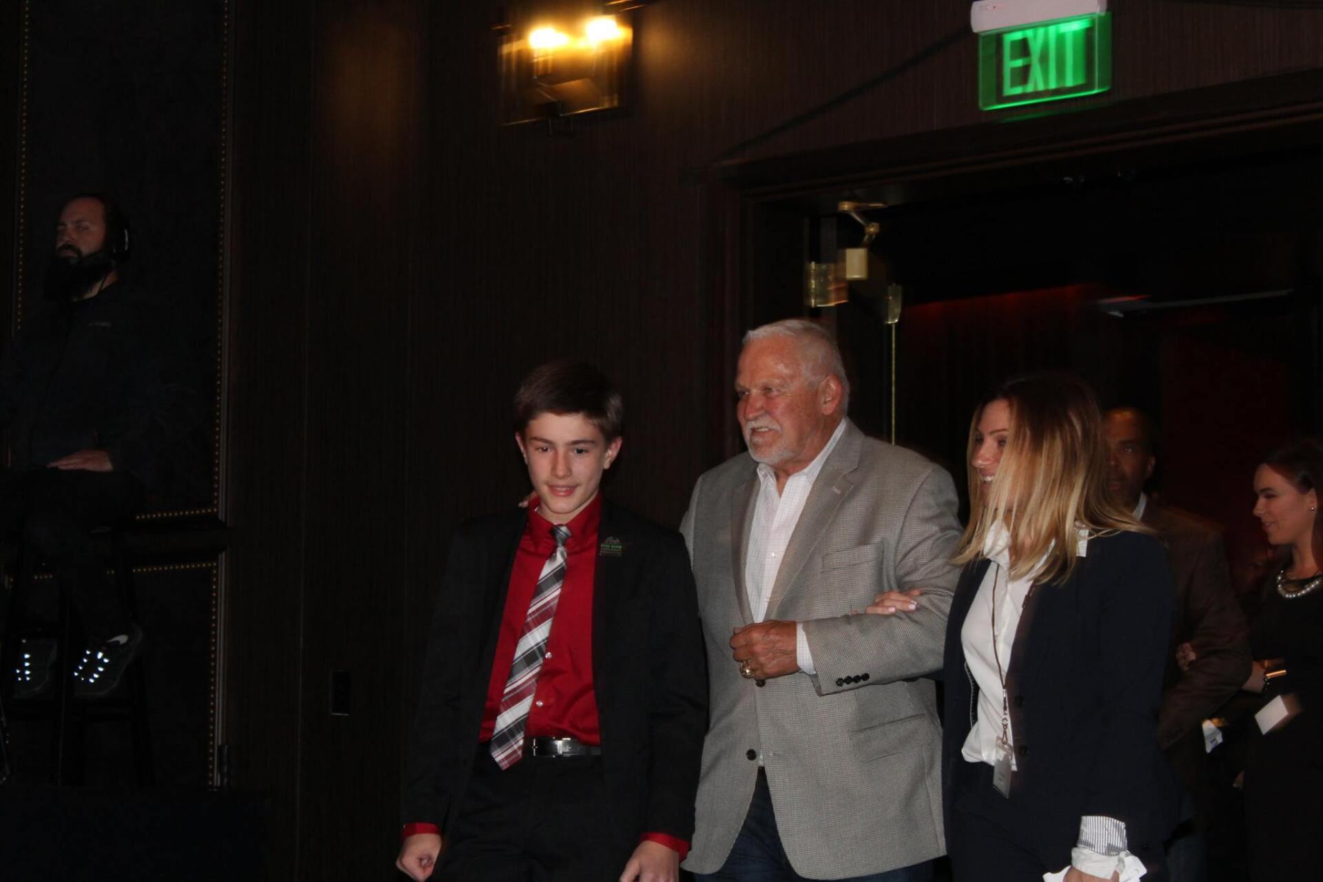 A group of people are walking in front of an exit sign.