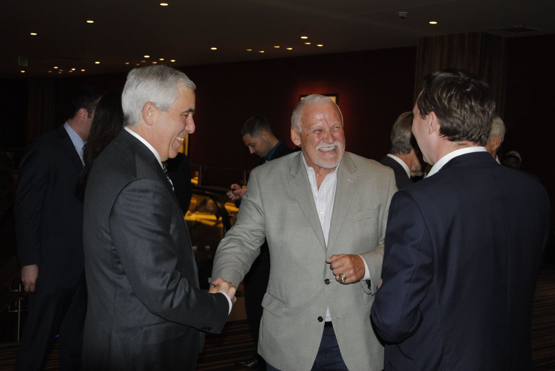 A group of men in suits are shaking hands in a room