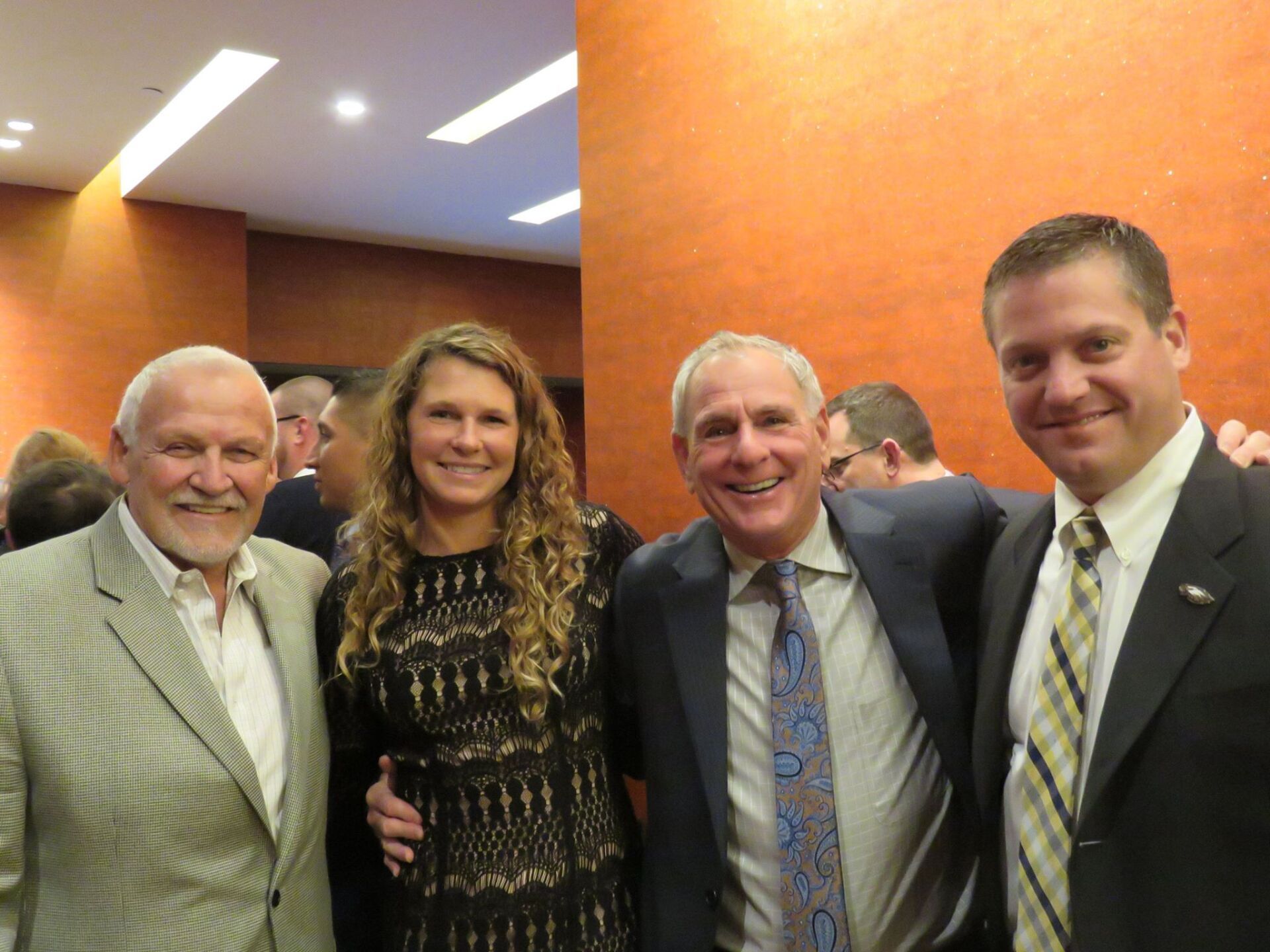 Three men and a woman are posing for a picture together
