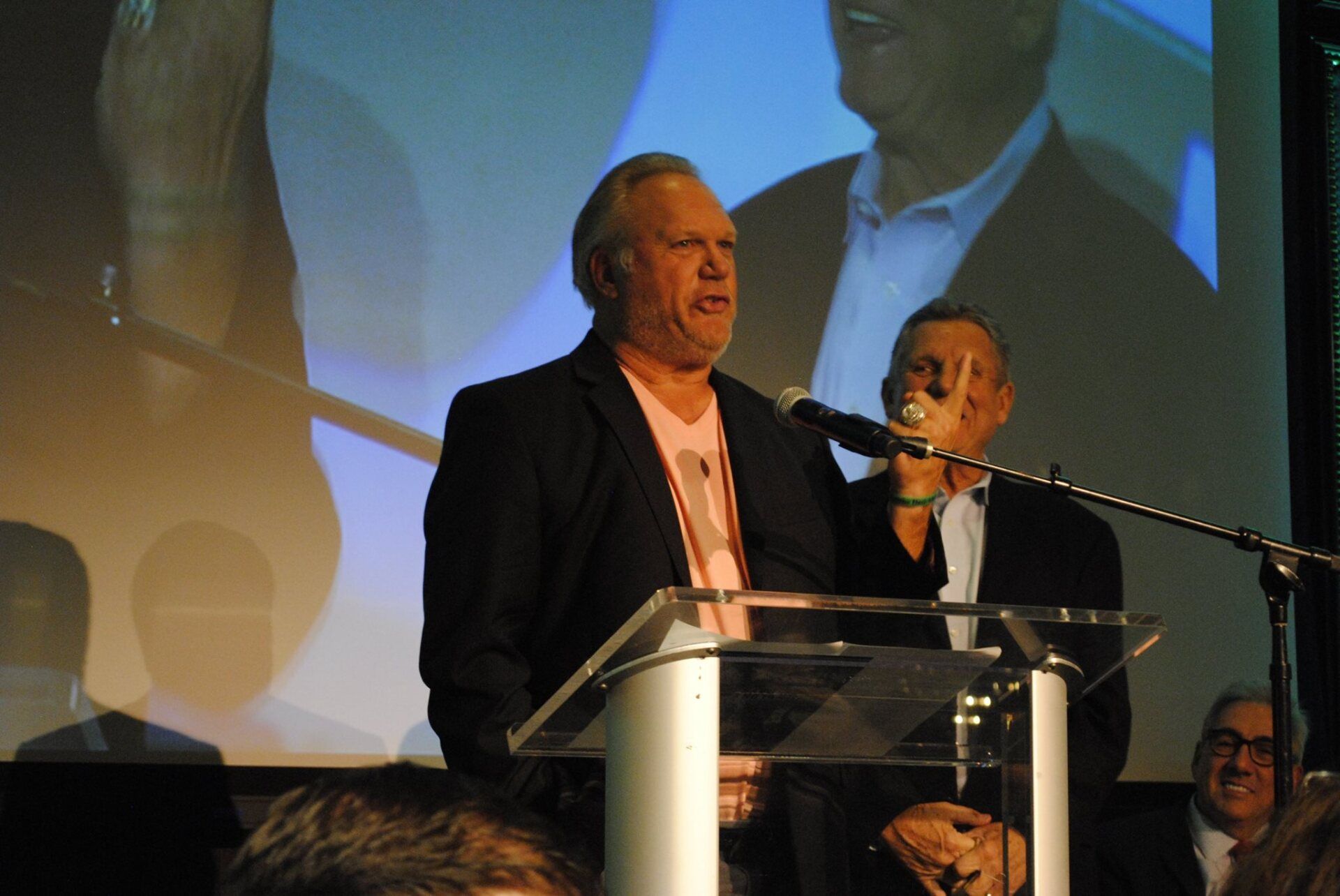 A man stands at a podium speaking into a microphone