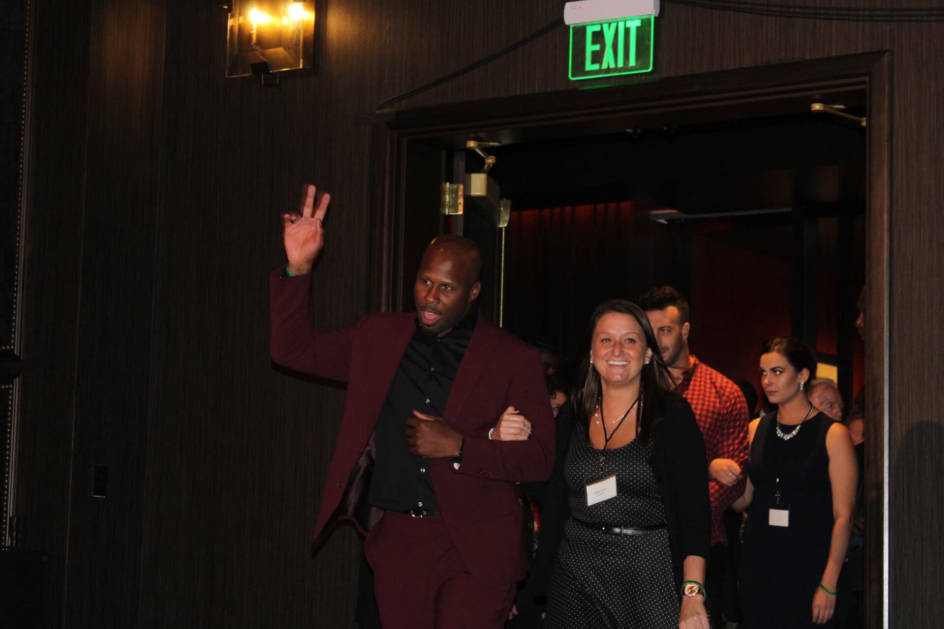 A group of people are walking through an exit sign.