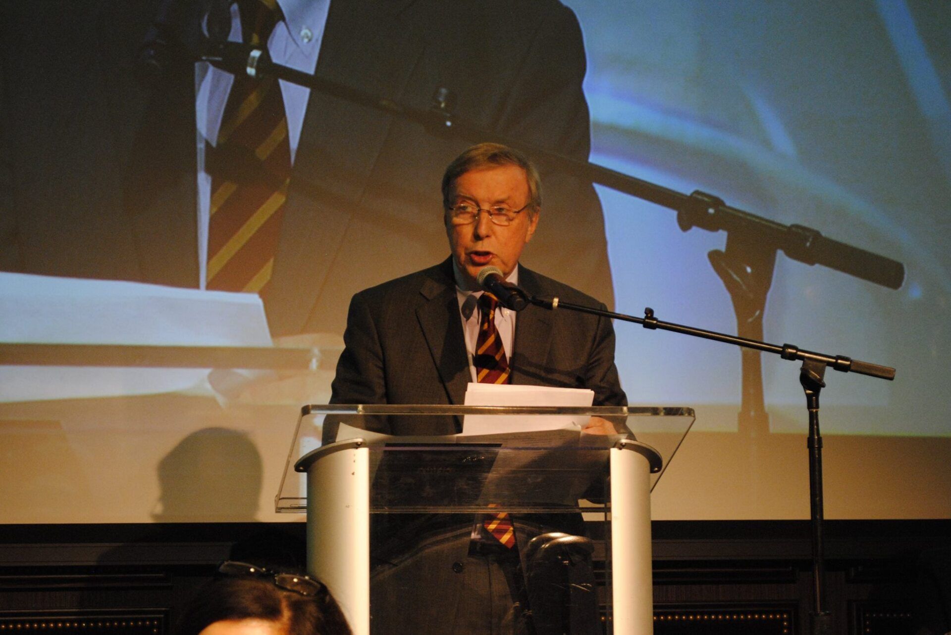 A man in a suit and tie is giving a speech at a podium