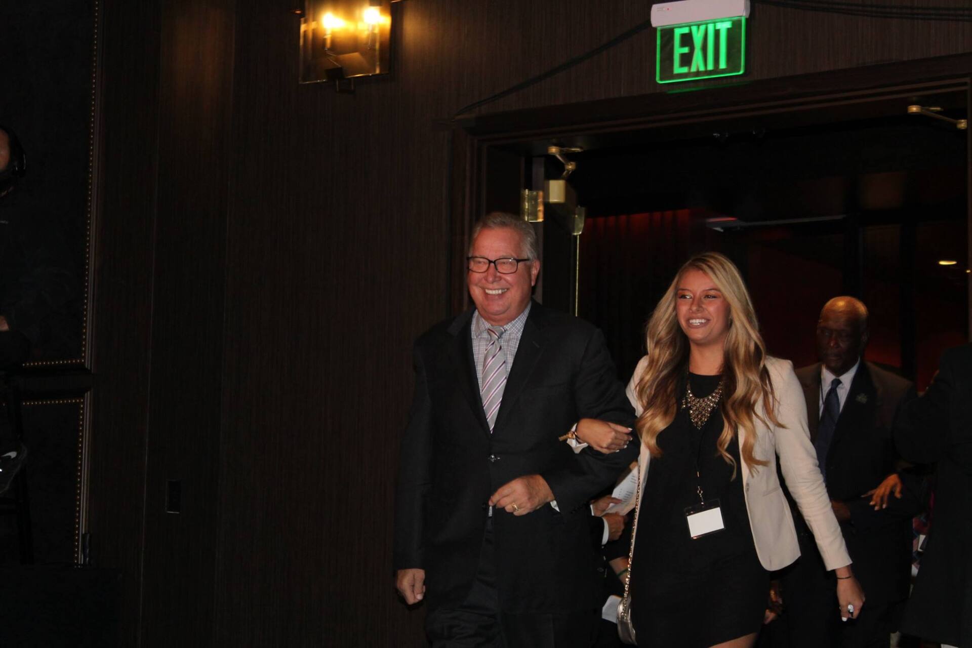 A man and a woman are walking in front of an exit sign