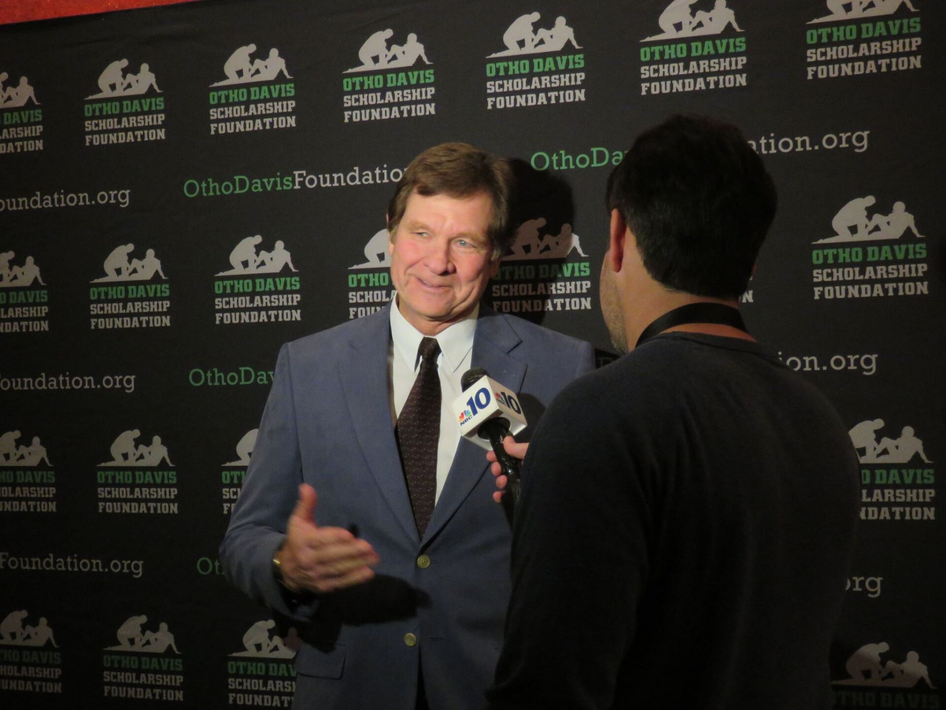 A man in a suit and tie is being interviewed by a reporter