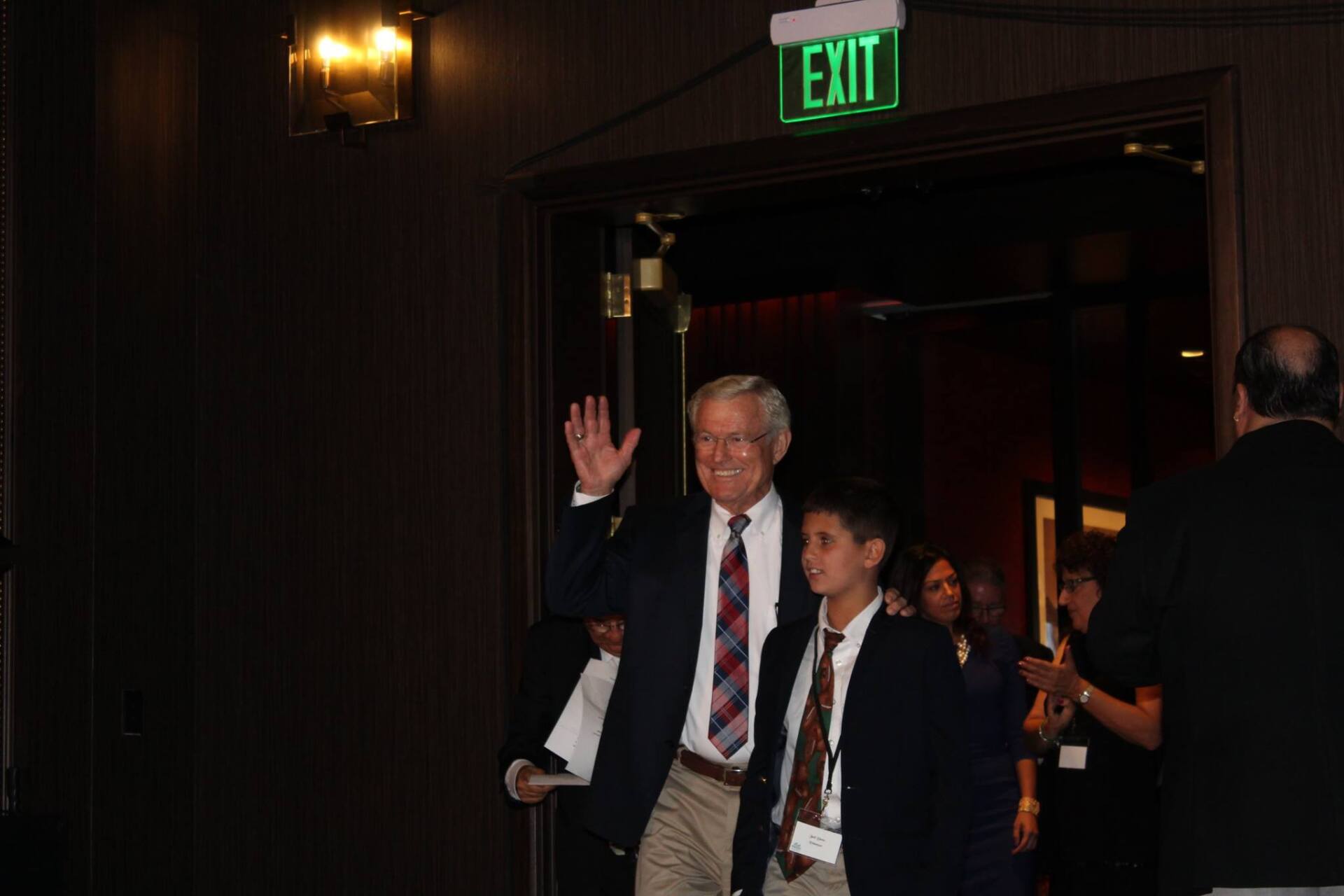 A man and a boy are walking through an exit sign