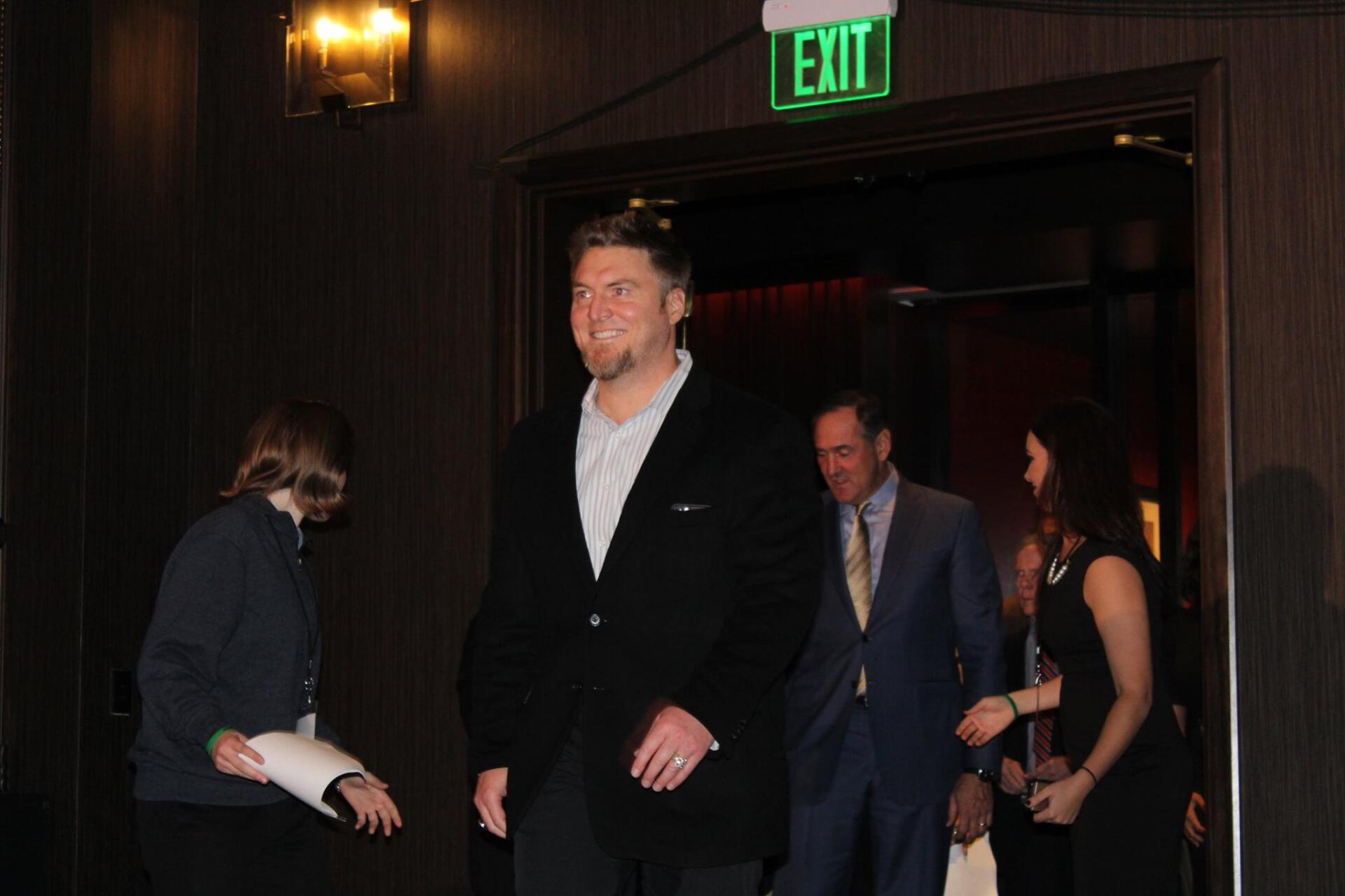 A man in a suit is walking through an exit sign