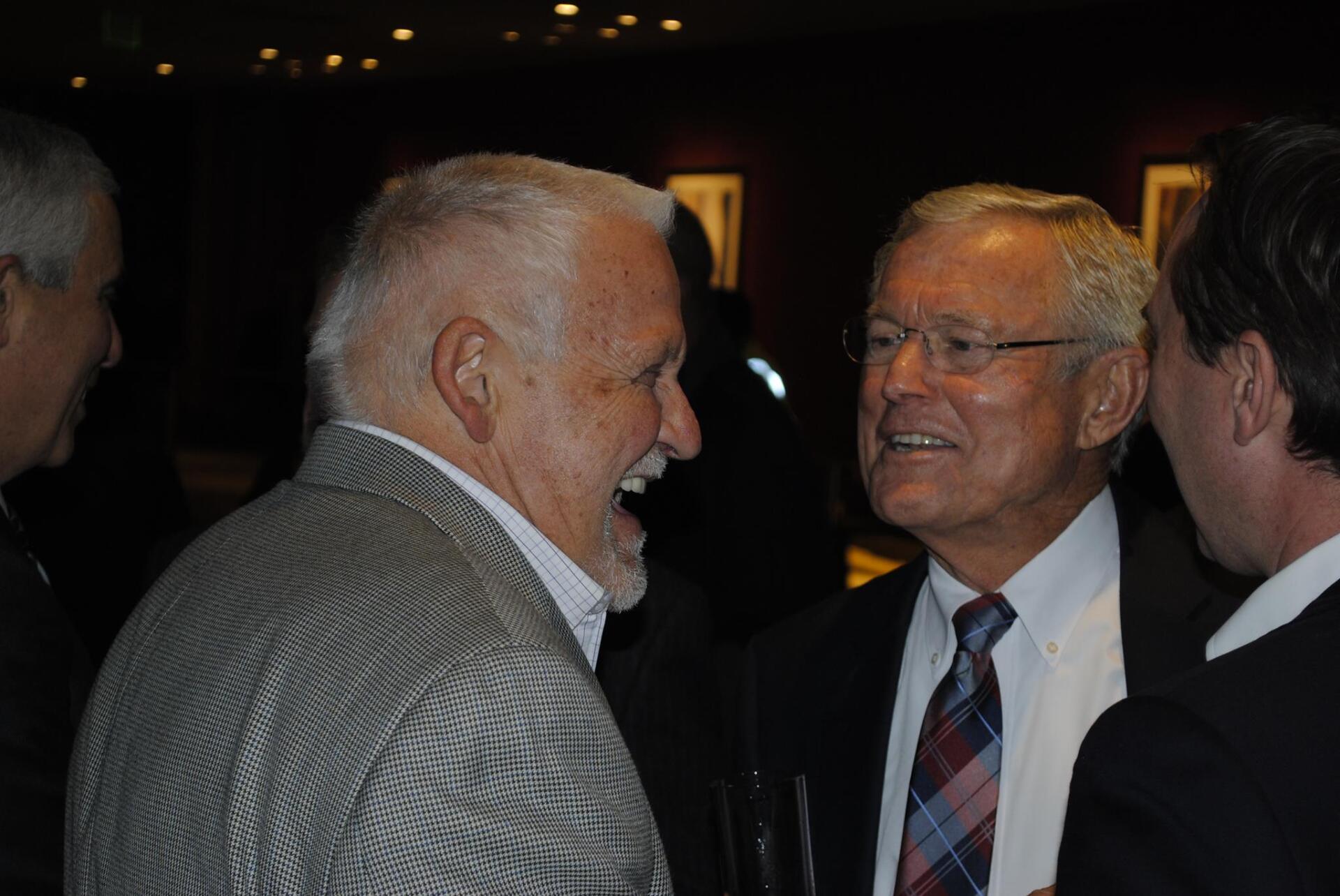 Three men in suits and ties are talking to each other