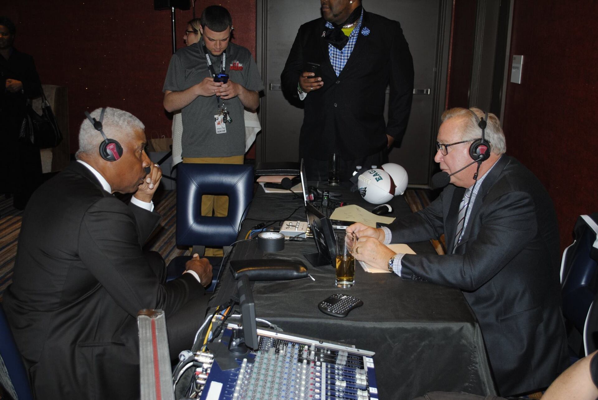 A group of men are sitting at a table with headphones on