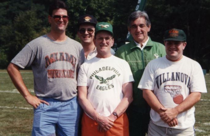 A group of men posing for a picture with one wearing a philadelphia eagles shirt