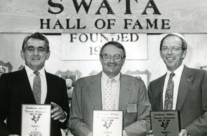 Three men are standing in front of a sign that says swata hall of fame