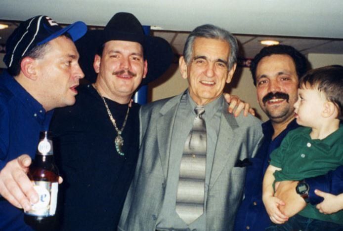 A group of men are posing for a picture and one man is holding a baby