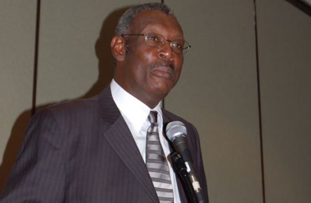 A man in a suit and tie is speaking into a microphone