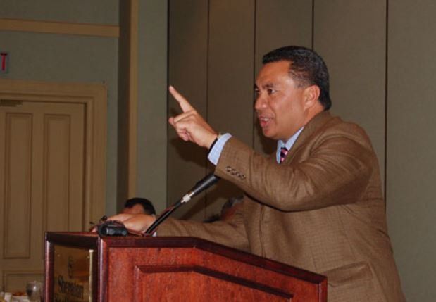 A man in a suit and tie is giving a speech at a podium
