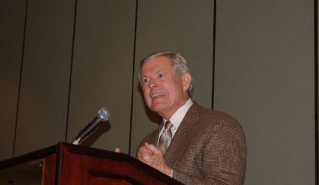 A man in a suit and tie is giving a speech at a podium