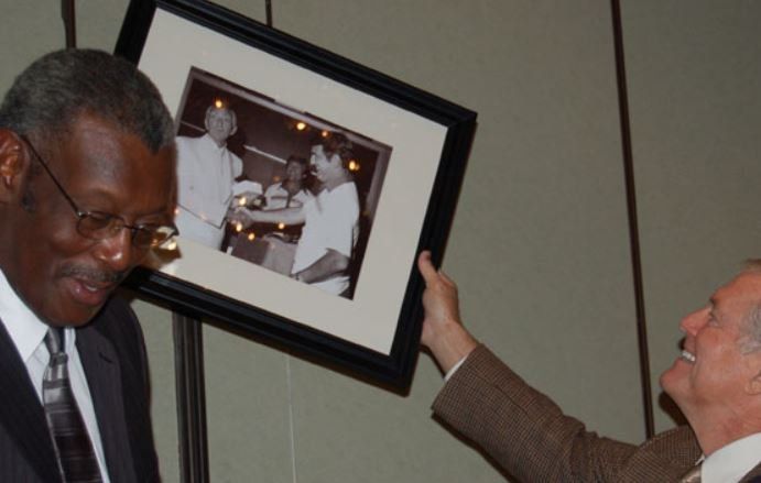 Two men are looking at a framed picture of a man and woman