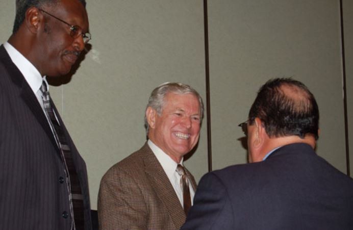 Three men in suits and ties are talking to each other