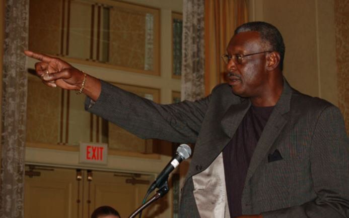 A man in a suit points to an exit sign